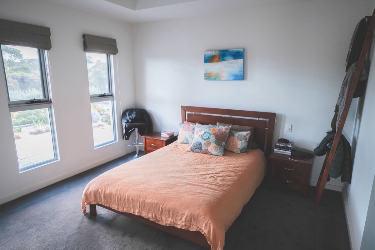 Chambre ordinaire éclairée par deux fenêtres, lit fait au centre de la pièce