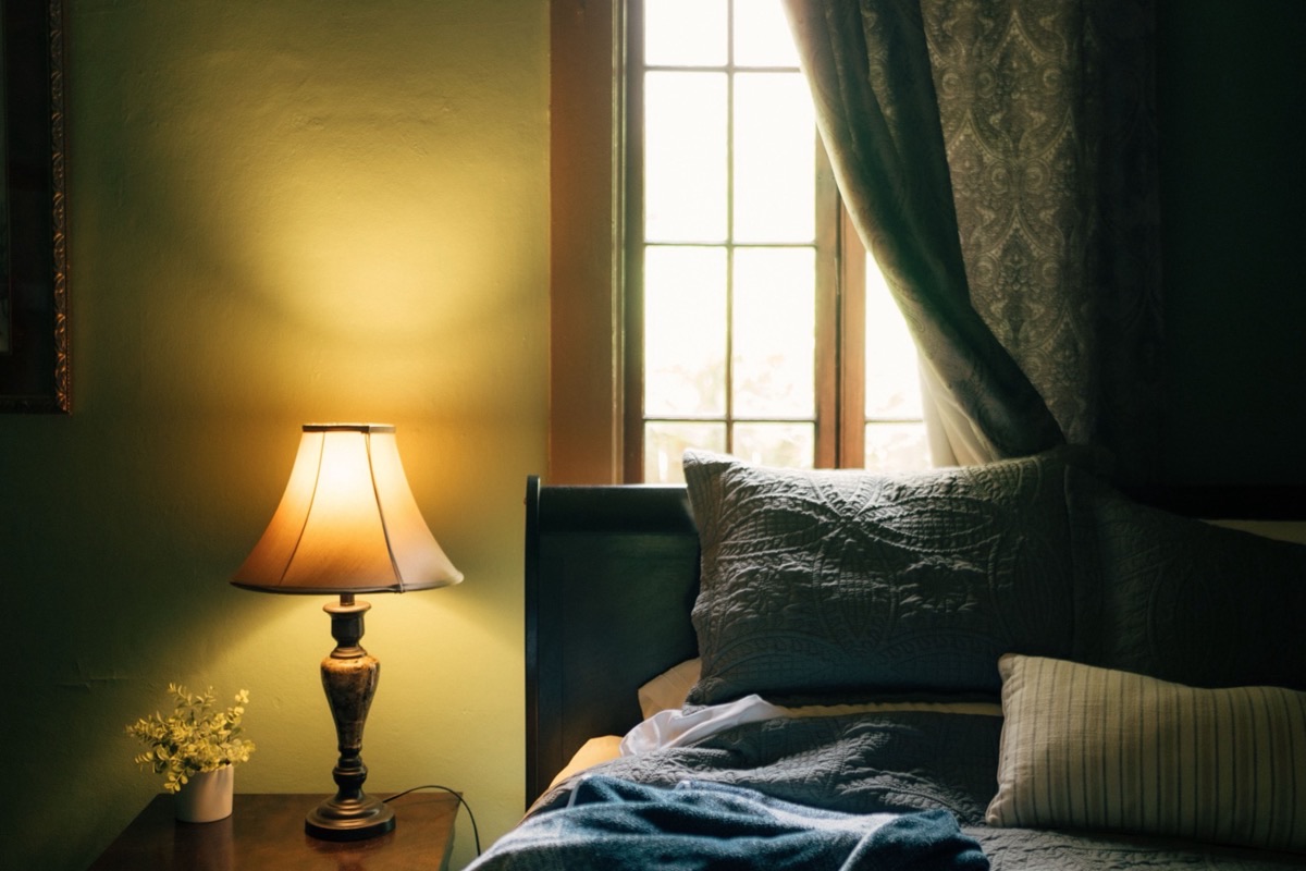 Chambre le soir éclairée par une lampe de chevet à lumière chaude et douce, lit au premier plan