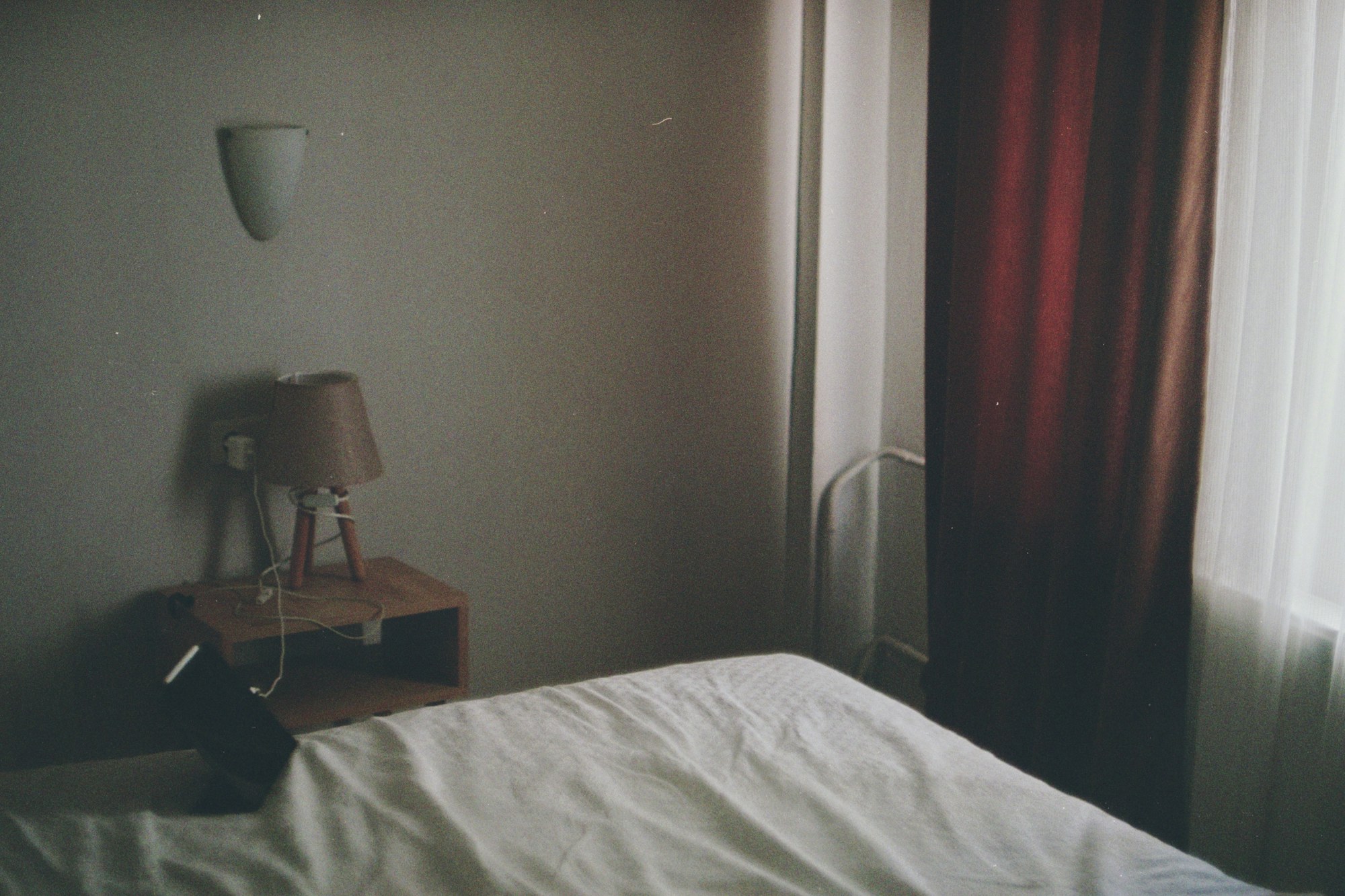 Chambre d hotel sobre dans une lumiere douce, lit et table de chevet