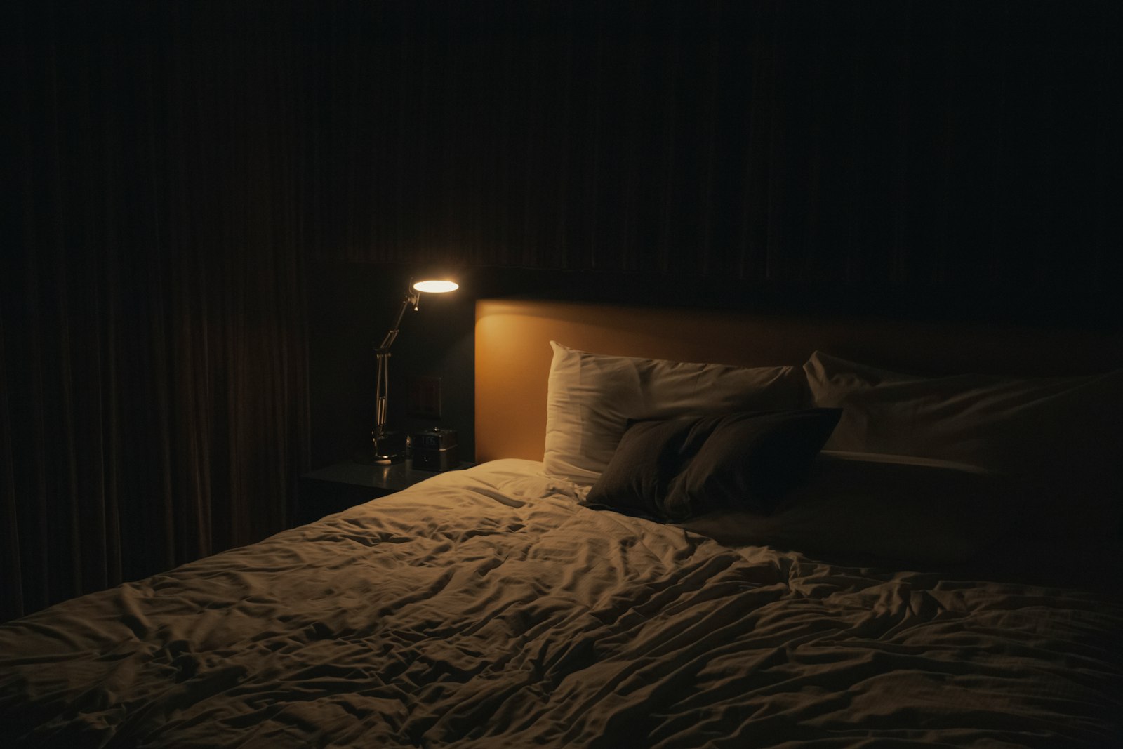 Lampe de chevet allumee pres du lit, chambre tamisee le soir