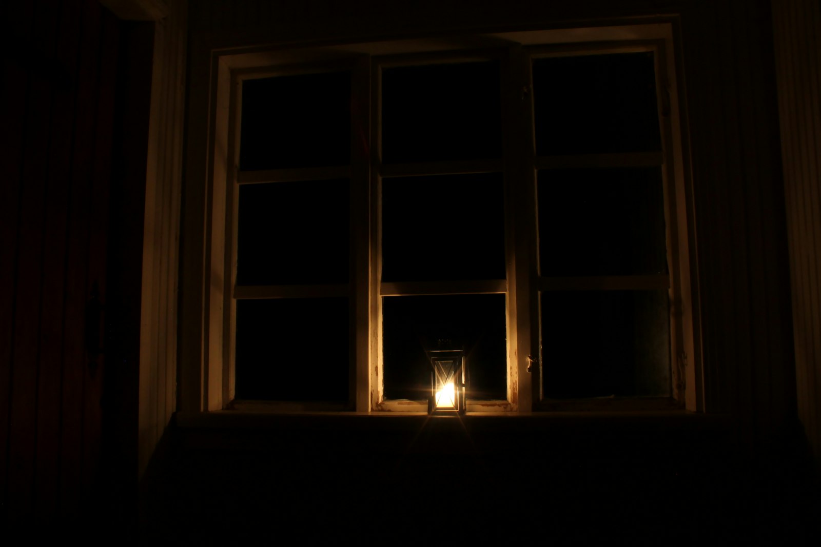 Bougie allumee devant une fenetre, ambiance calme du soir